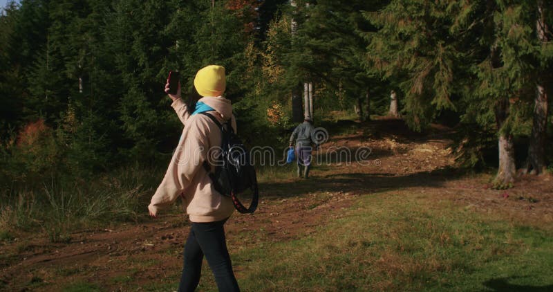 Femme en beanie jaune prenant un selfie dans la forêt. activité extérieure et concept de médias sociaux. conception de l'affiche clips vidéos
