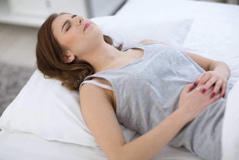 Femme en douleur se trouvant sur le lit photographie stock libre de droits Femme en douleur se trouvant sur le lit photographie stock libre de droits
