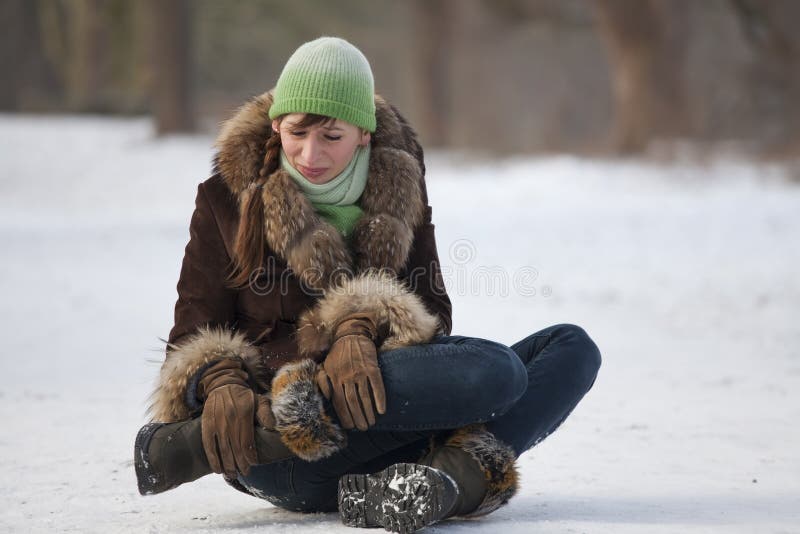 Woman in pain holds her knee after slipping on snowy road. Woman in pain holds her knee after slipping on snowy road