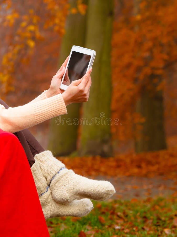 Femme dans un parc automnal utilisant une tablette photo libre de droits