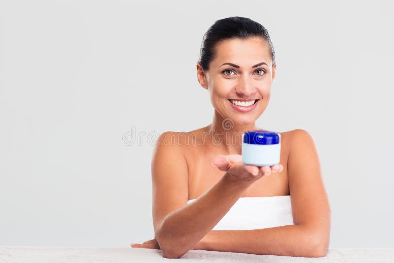 Femme en serviette se reposant à la table et tenant le pot crème