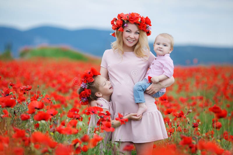 Femme enceinte avec des enfants dans un domaine des pavots rouges photo libre de droits Femme enceinte avec des enfants dans un domaine des pavots rouges photo libre de droits