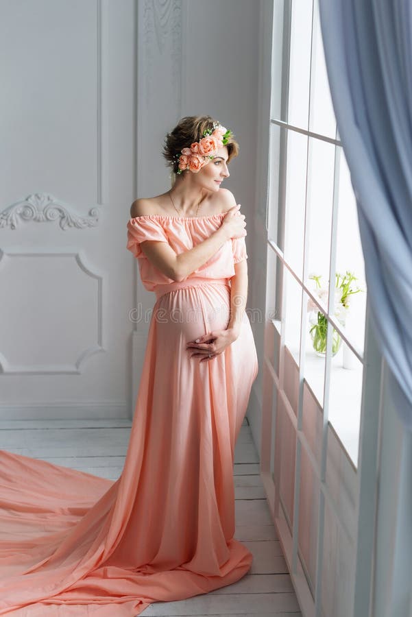 Femme Enceinte Dans La Robe De Soirée Rose Se Tenant Près De