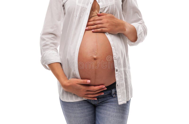 Femme enceinte dans une chemise blanche et des jeans sur un fond blanc photographie stock Femme enceinte dans une chemise blanche et des jeans sur un fond blanc photographie stock