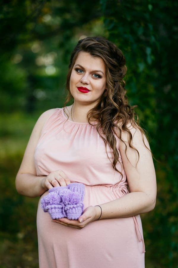 Femme enceinte de jeunes dans la robe rose avec des butins images libres de droits Femme enceinte de jeunes dans la robe rose avec des butins images libres de droits