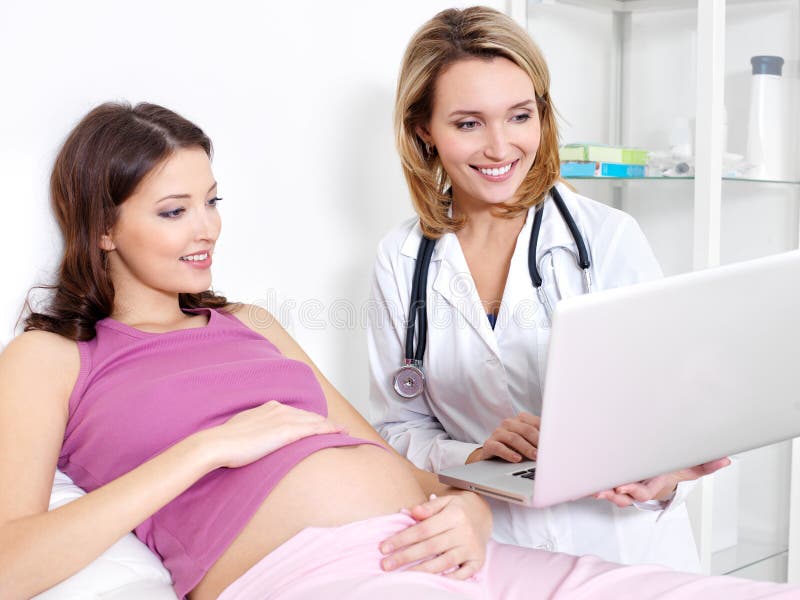 Femme enceinte et docteur avec l'ordinateur portatif