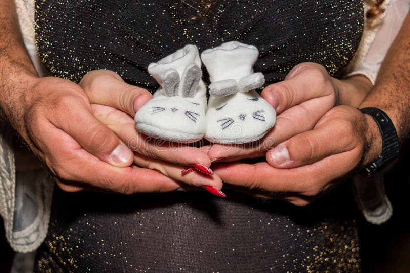 Femme enceinte et homme tenant des chaussures de bébé photo stock Femme enceinte et homme tenant des chaussures de bébé photo stock