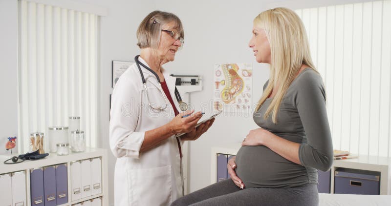 Femme enceinte heureuse parlant avec le docteur image libre de droits Femme enceinte heureuse parlant avec le docteur image libre de droits