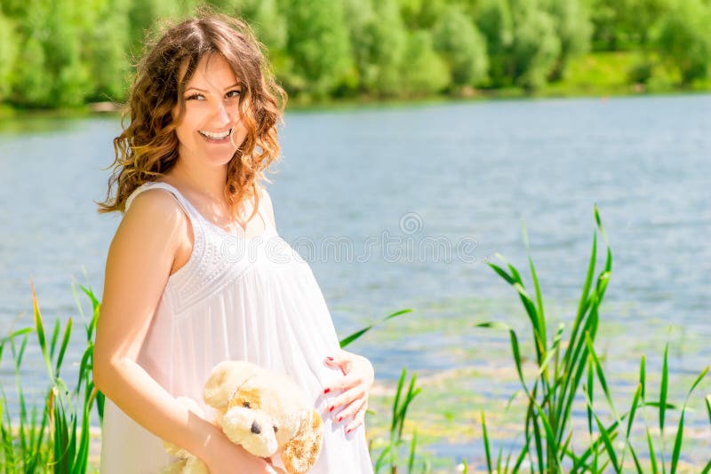 Femme enceinte heureuse posant sur la nature image libre de droits Femme enceinte heureuse posant sur la nature image libre de droits