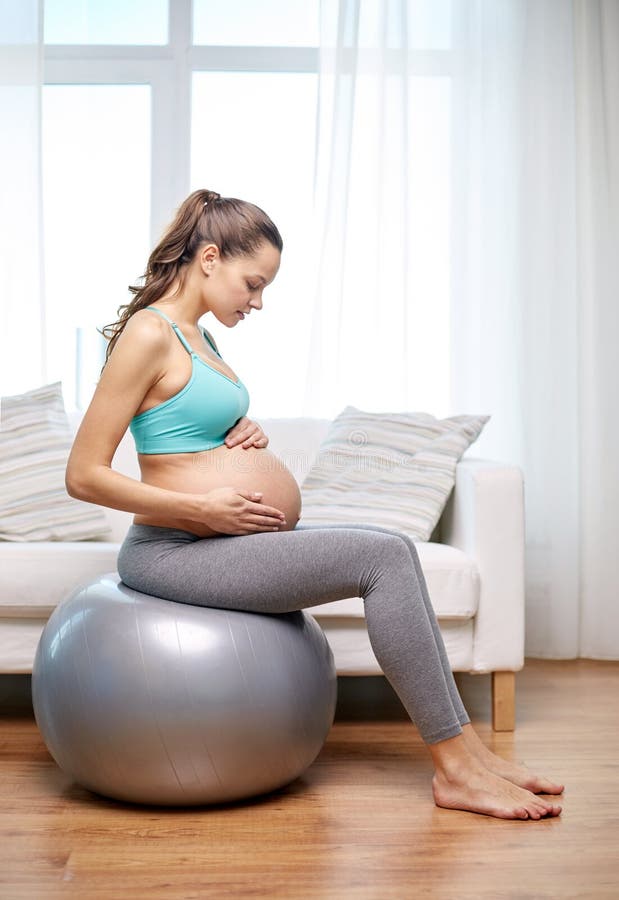 Femme enceinte heureuse s'exerçant sur le fitball à la maison photo stock Femme enceinte heureuse s'exerçant sur le fitball à la maison photo stock