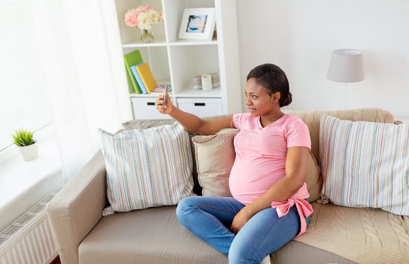 Femme enceinte prenant le selfie de smartphone à la maison photo libre de droits Femme enceinte prenant le selfie de smartphone à la maison photo libre de droits