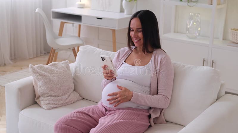 Femme enceinte qui passe du temps libre en ligne avec son téléphone tout en se reposant à la maison banque de vidéos