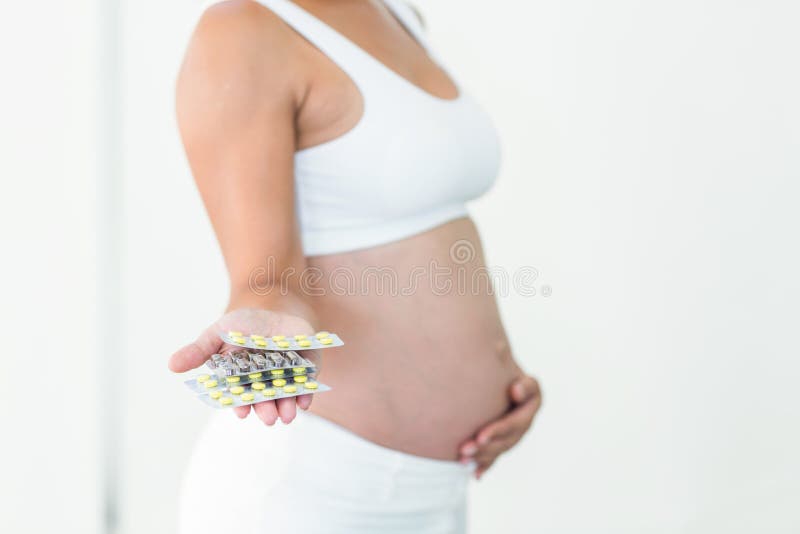 Femme enceinte tenant des pilules de vitamine photo stock Femme enceinte tenant des pilules de vitamine photo stock