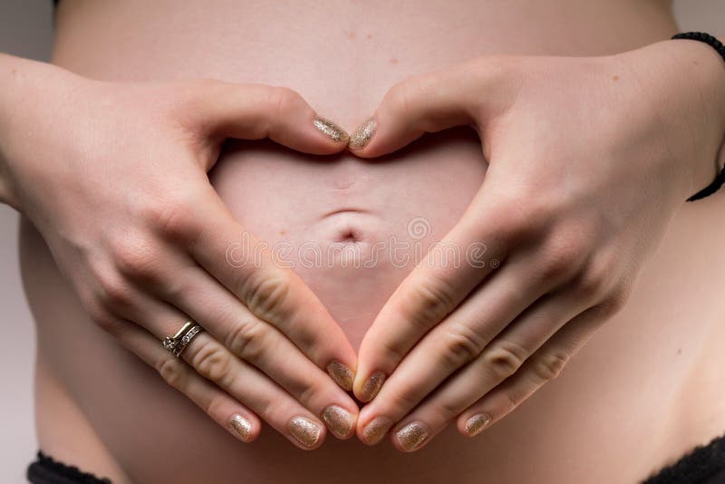 An image of pregnant Woman holding her hands in a heart shape on her baby bu. An image of pregnant Woman holding her hands in a heart shape on her baby bu