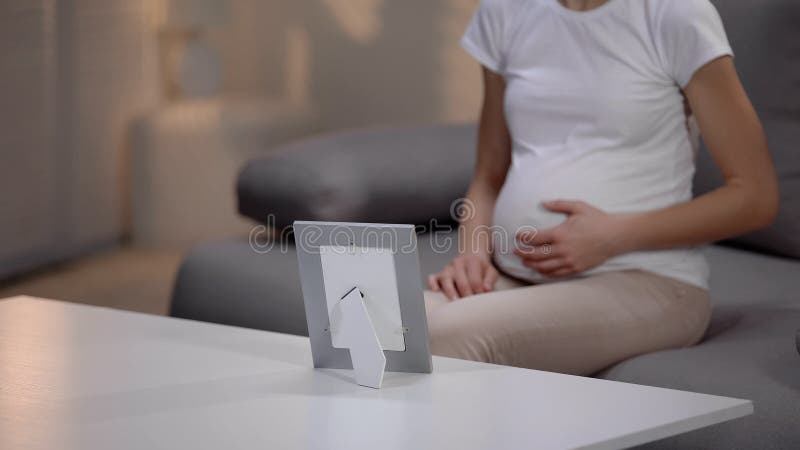Femme enceinte touchant le ventre et regardant la photo disparu de relatif images stock Femme enceinte touchant le ventre et regardant la photo disparu de relatif images stock