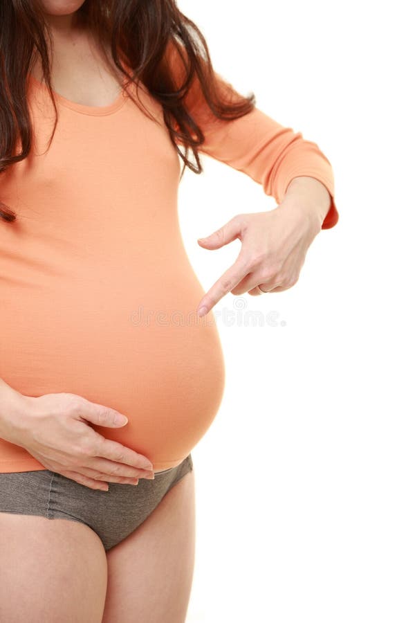 Femme enceinte utilisant la chemise orange indiquant son estomac images libres de droits Femme enceinte utilisant la chemise orange indiquant son estomac images libres de droits
