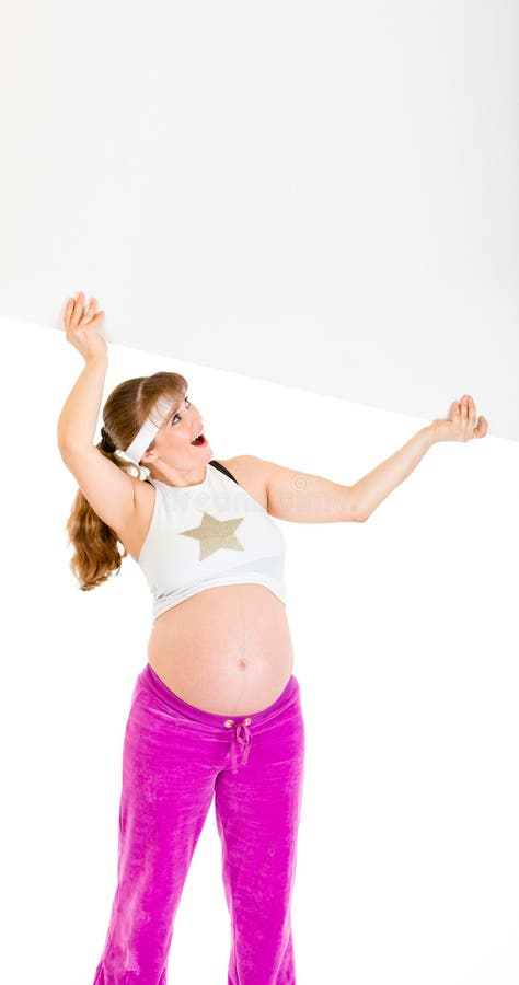 Femme enceinte étonné retenant le panneau-réclame blanc image libre de droits Femme enceinte étonné retenant le panneau-réclame blanc image libre de droits