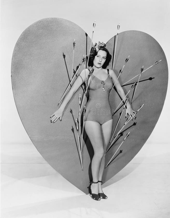 Femme entourée par des flèches sur le coeur énorme (toutes les personnes représentées ne sont pas plus long vivantes et aucun dom photo stock Femme entourée par des flèches sur le coeur énorme (toutes les personnes représentées ne sont pas plus long vivantes et aucun dom photo stock