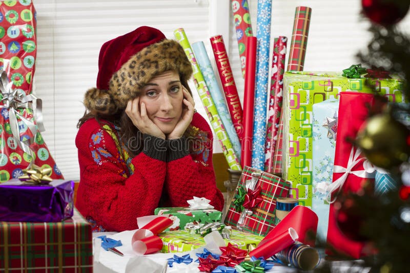 Femme enveloppant des cadeaux de Noël, semblant épuisés photos libres de droits Femme enveloppant des cadeaux de Noël, semblant épuisés photos libres de droits