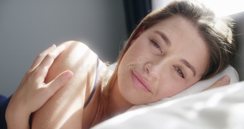 Femme face et se détendre dans le lit à la maison souriant et se reposer dans la chambre le week-end. portrait de femme heureuse