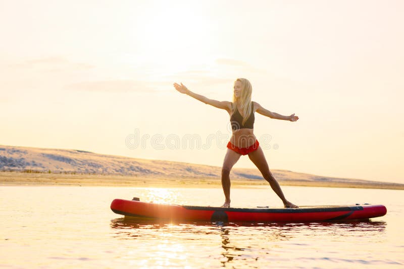 Femme faisant des exercices de yoga sur le panneau de palette dans l'eau photographie stock Femme faisant des exercices de yoga sur le panneau de palette dans l'eau photographie stock