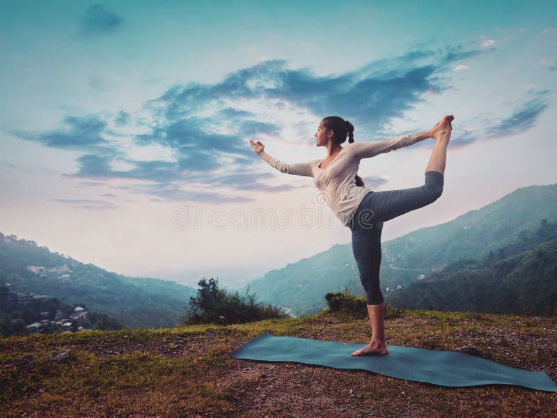 Femme faisant l'asana Natarajasana de yoga dehors sur le coucher du soleil image stock Femme faisant l'asana Natarajasana de yoga dehors sur le coucher du soleil image stock