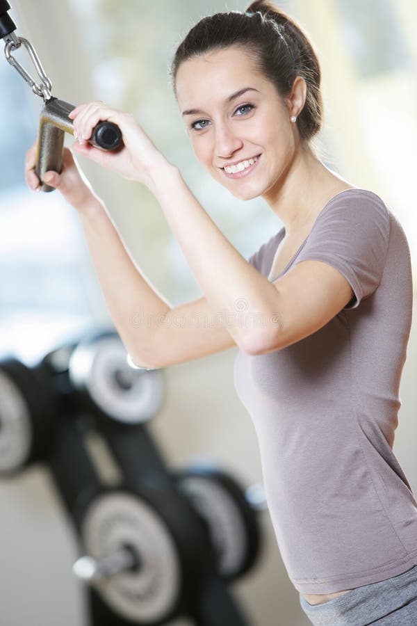 Femme faisant sur une machine de poids au club de santé images libres de droits Femme faisant sur une machine de poids au club de santé images libres de droits
