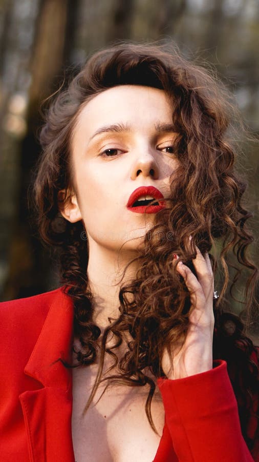 Femme fascinante utilisant l'équipement rouge et assortissant le lustre rouge de lèvre photographie stock libre de droits Femme fascinante utilisant l'équipement rouge et assortissant le lustre rouge de lèvre photographie stock libre de droits