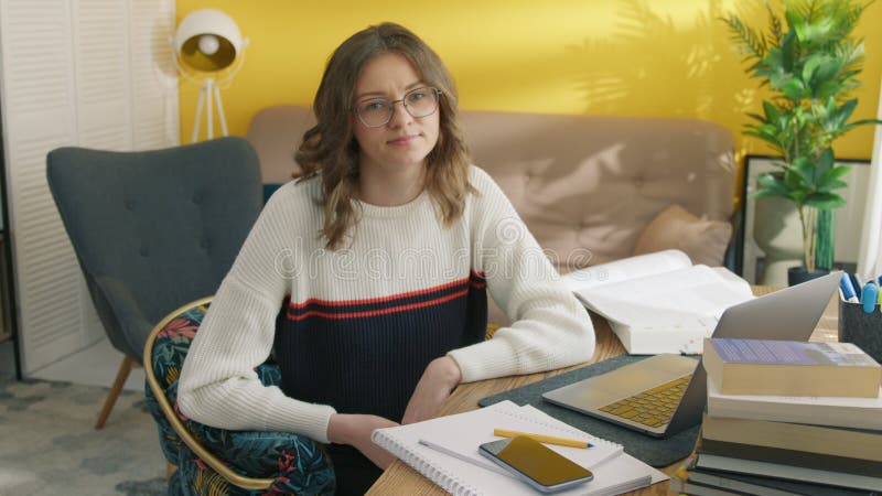 Femme fille assise à la table de travail à la maison. élève posant devant une caméra clips vidéos