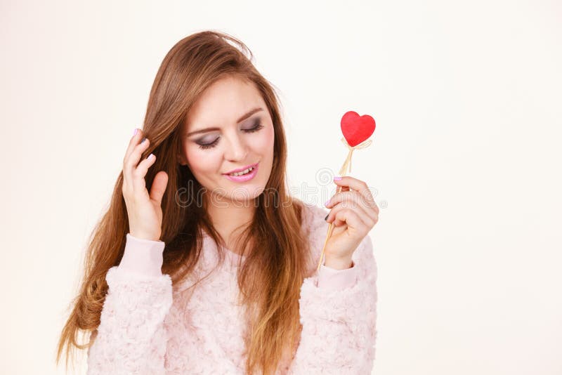 Femme Flirty tenant le coeur en bois rouge sur le b?ton images stock Femme Flirty tenant le coeur en bois rouge sur le b?ton images stock
