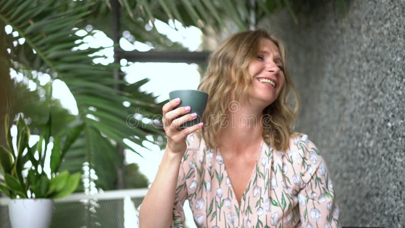 Femme heureuse assise dans un café avec une tasse de café clips vidéos