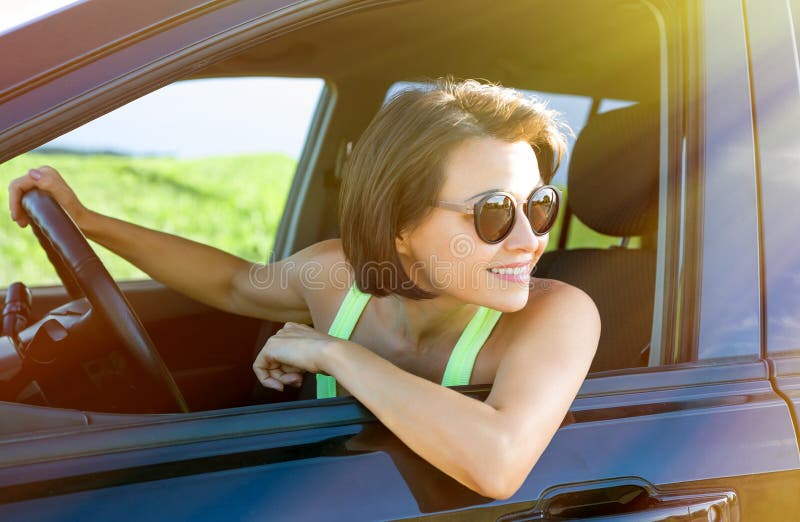 Femme heureuse attirante s'asseyant en portrait automobile d'été extérieur images stock Femme heureuse attirante s'asseyant en portrait automobile d'été extérieur images stock