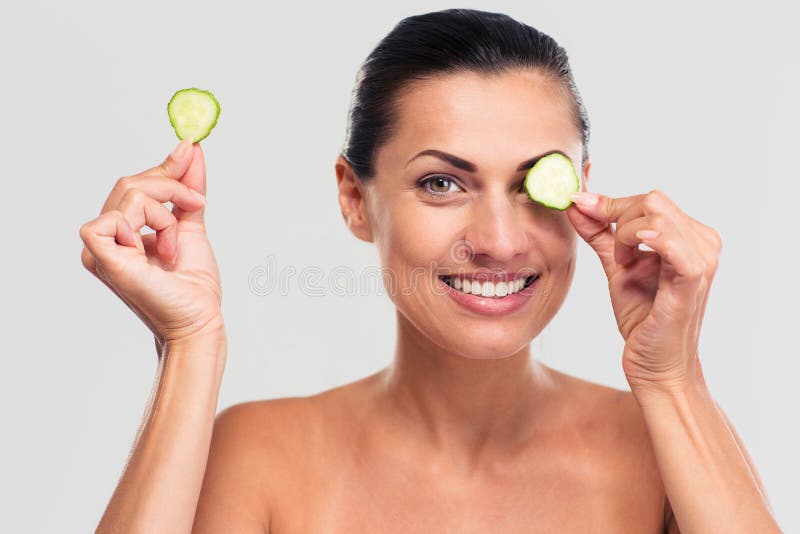 Femme heureuse couvrant son oeil de concombre