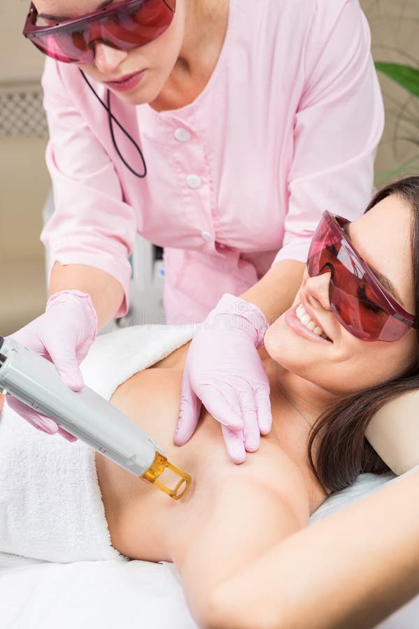 Femme heureuse de client ayant la procédure d'épilation de laser d'aisselle Service professionnel de soin de beauté de peau dans photo libre de droits Femme heureuse de client ayant la procédure d'épilation de laser d'aisselle Service professionnel de soin de beauté de peau dans photo libre de droits