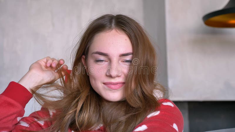 Femme heureuse de gingembre utilisant les pyjamas rouges et regardant l'appareil-photo, sourire, se reposant sur le divan dans le banque de vidéos