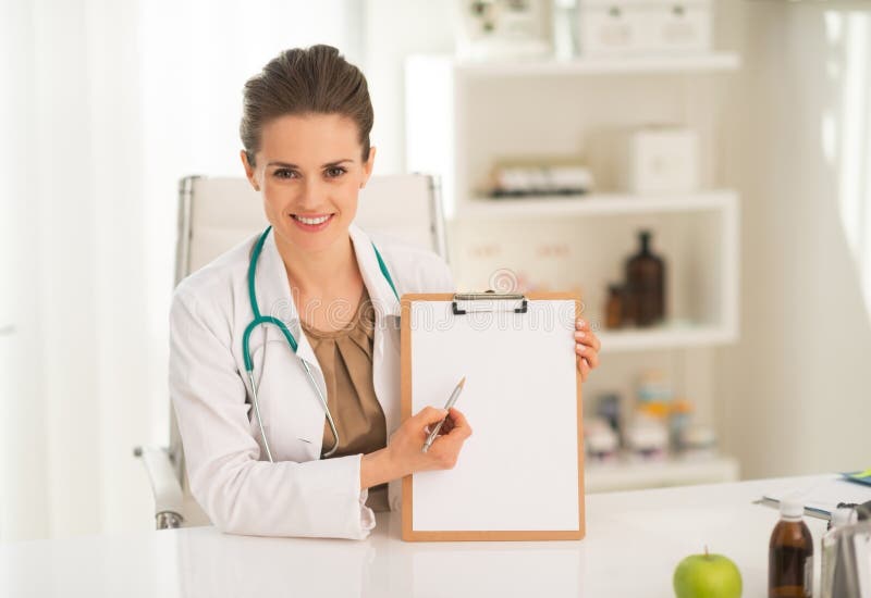 Femme heureuse de médecin se dirigeant dans le presse-papiers photographie stock libre de droits Femme heureuse de médecin se dirigeant dans le presse-papiers photographie stock libre de droits