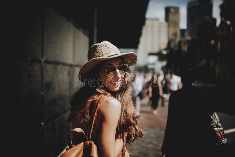 Femme heureuse de sourire marchant dans une rue de Sydney et tournant autour pour regarder l'appareil-photo images stock Femme heureuse de sourire marchant dans une rue de Sydney et tournant autour pour regarder l'appareil-photo images stock