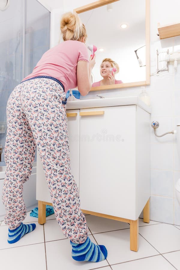 Femme heureuse employant la brosse de nettoyage faciale photo libre de droits Femme heureuse employant la brosse de nettoyage faciale photo libre de droits