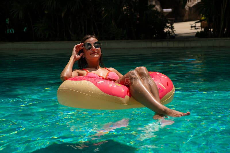 Femme heureuse et anneau gonflable de bain dans la forme d'un beignet dans la piscine images libres de droits Femme heureuse et anneau gonflable de bain dans la forme d'un beignet dans la piscine images libres de droits