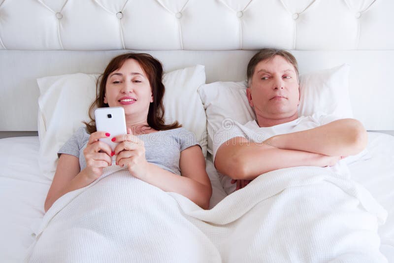 Femme heureuse et homme malheureux dans la chambre à coucher, couple de Moyen Âge, problème de famille photographie stock Femme heureuse et homme malheureux dans la chambre à coucher, couple de Moyen Âge, problème de famille photographie stock