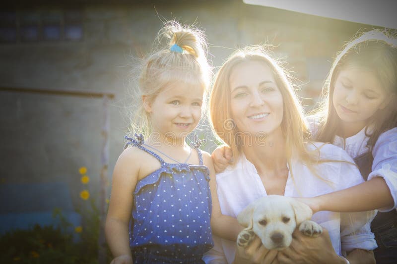 Femme heureuse et ses filles avec le chiot de Labrador photographie stock Femme heureuse et ses filles avec le chiot de Labrador photographie stock