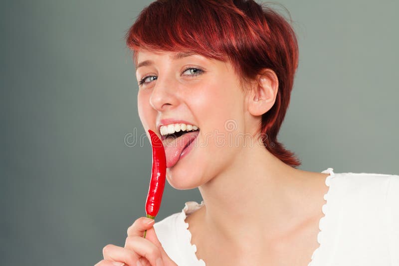 Femme heureuse léchant le piment photos stock Femme heureuse léchant le piment photos stock