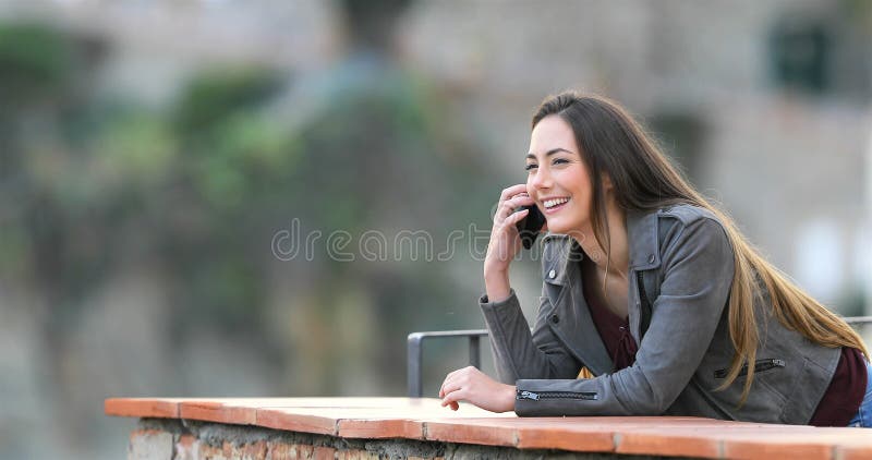 Femme heureuse parlant au téléphone dans un balcon banque de vidéos