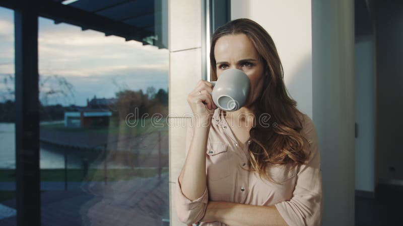 Femme heureuse restant près de la fenêtre après jour ouvrable Femme décontractée ayant le repos