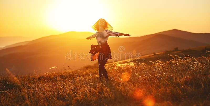 Femme heureuse sautant et appréciant la vie au coucher du soleil en montagnes