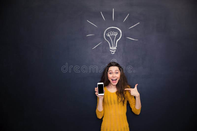 Femme heureuse se dirigeant sur l'écran vide de smartphone au-dessus du fond de tableau images stock Femme heureuse se dirigeant sur l'écran vide de smartphone au-dessus du fond de tableau images stock