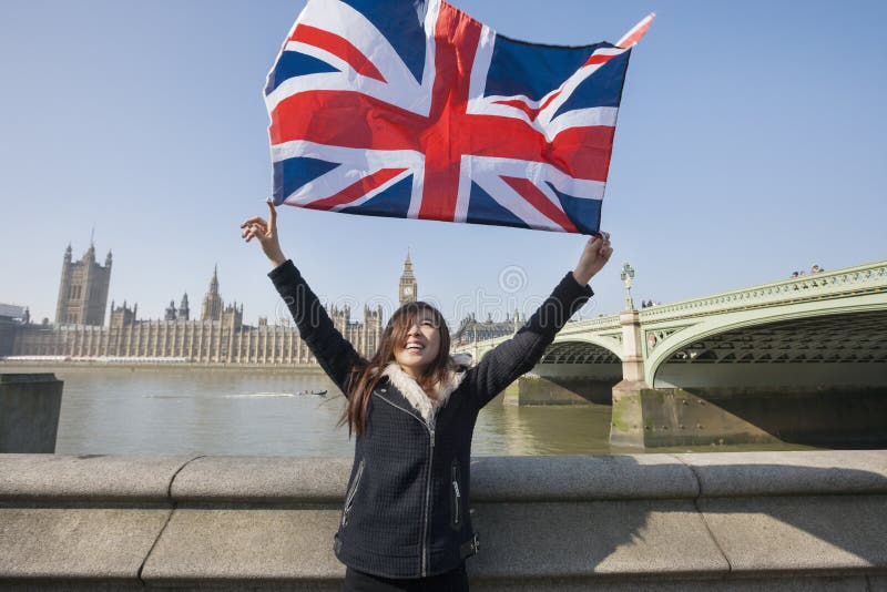 Femme heureuse tenant le drapeau britannique tout en se tenant contre Big Ben à Londres, Angleterre, R-U photos libres de droits Femme heureuse tenant le drapeau britannique tout en se tenant contre Big Ben à Londres, Angleterre, R-U photos libres de droits