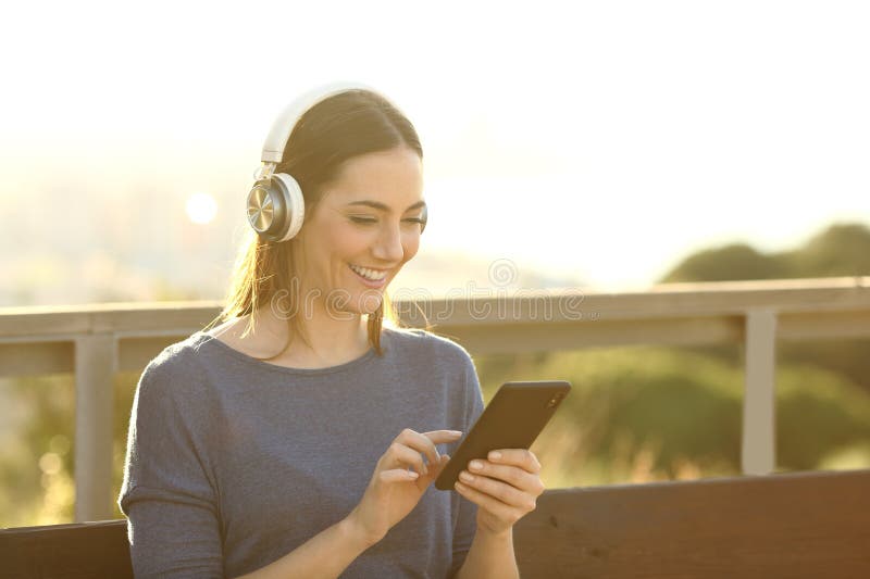 Femme heureuse écoutant de la musique par téléphone dehors photo libre de droits