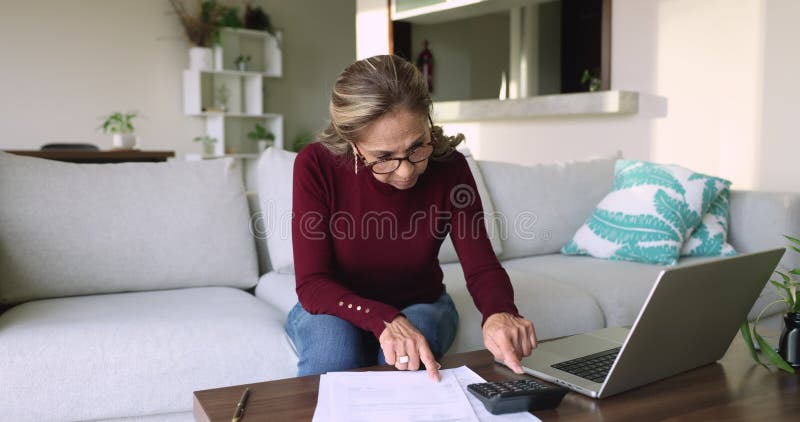 Femme hispanique mature à la retraite concentrée compte des dépenses sur calculatrice clips vidéos