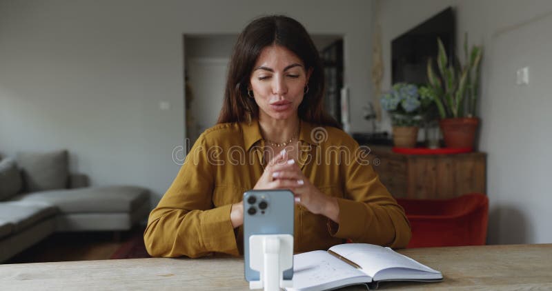 Femme hispanique participant à une réunion virtuelle avec son smartphone banque de vidéos